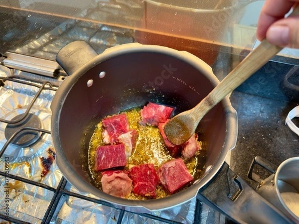 Fototapeta Carne em cubos cortas sobre a mesa com fundo desfocado e cebolas e panela con nivel de agua.
