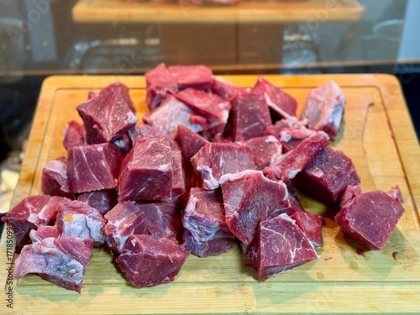 Fototapeta Carne em cubos cortas sobre a mesa com fundo desfocado e cebolas e panela con nivel de agua.