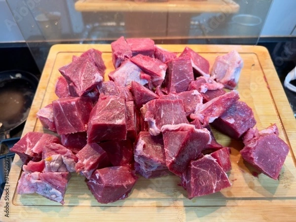 Fototapeta Carne em cubos cortas sobre a mesa com fundo desfocado e cebolas e panela con nivel de agua.