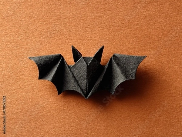 Fototapeta Minimalistic Black Origami Bat: Flat Lay View on Orange Background, Suitable for Halloween Decor, Posters & Creative Commercial Visuals