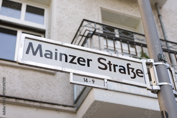 Fototapeta Mainzer Strasse street name sign in Berlin, Germany. Road signage at the intersection. Close up of the location guide showing the direction of the street in Friedrichshain.
