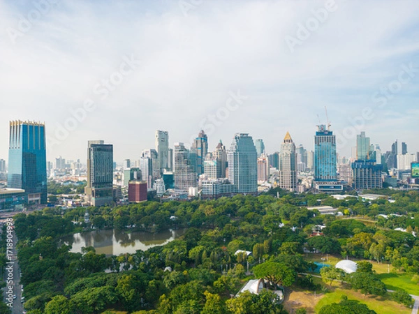 Fototapeta Aerial view green tree forest Lumpini public park with modern office building agiant blue sky cloud