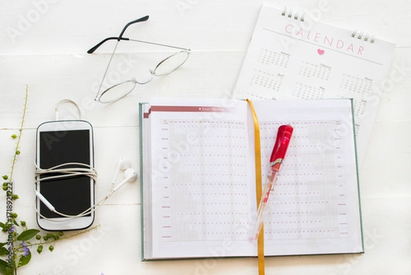 Fototapeta notebook, mobile phone and calendar for planner business work arrangement flat lay style on background white