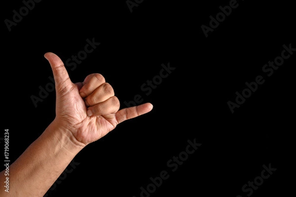 Fototapeta Close-Up of Hand Making Shaka Gesture with Black Background