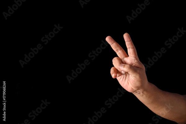 Fototapeta Hand Displaying Peace Gesture Against Black Background