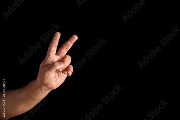 Fototapeta Hand Displaying Peace Gesture Against Black Background
