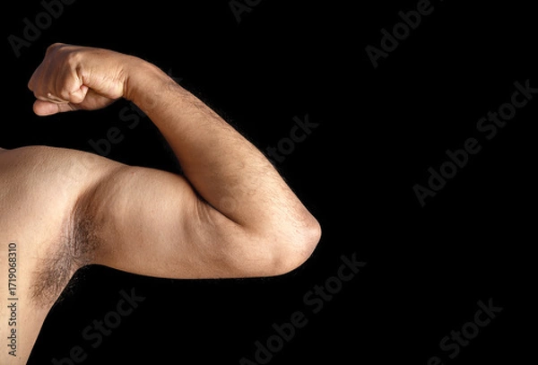 Fototapeta Close-Up of Flexed Bicep Connoting Strength and Fitness on a Black Background