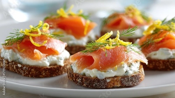 Fototapeta Five canap?s of smoked salmon atop creamy cheese spread on dark bread rounds, garnished with lemon zest and dill sprigs, arranged on a white plate