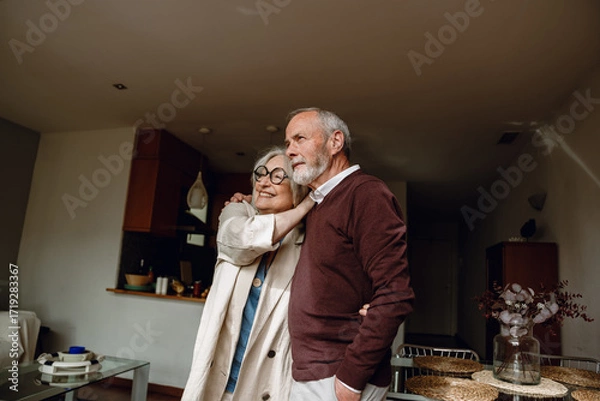 Fototapeta A man and a woman are hugging and looking ahead while she smiles
