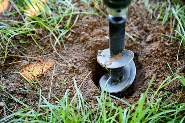 Obraz Garden auger drill bit digging hole in soil for planting and construction work