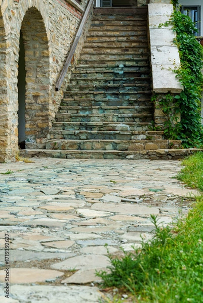 Fototapeta view of stone steps of an old house with arches and porch