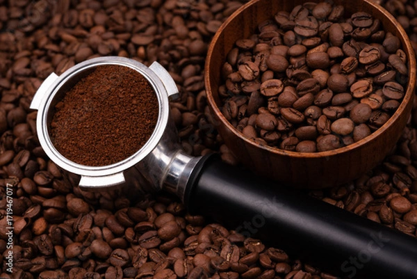 Fototapeta Holder with ground coffee on the background of roasted coffee beans with wooden cup. Coffee horn and coffee beans background texture.