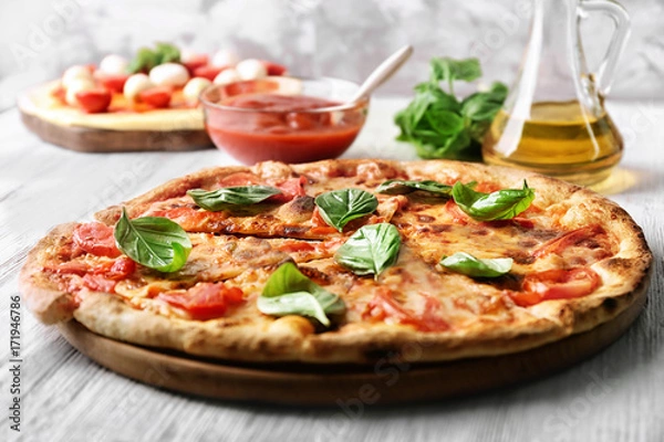 Obraz Pyszna pizza z pomidorami i świeżą bazylią na stole kuchennym