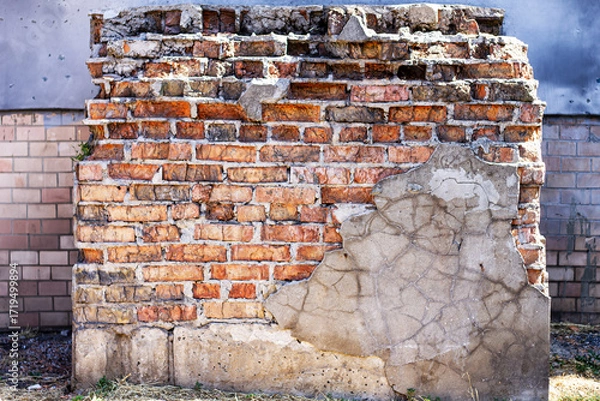 Fototapeta A weathered, crumbling brick wall with peeling plaster, a vivid symbol of urban decay. The texture and destruction are highlighted, showing the passage of time.

