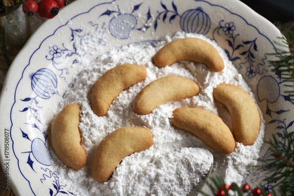 Fototapeta Making homemade Christmas cookies called Kipferl - coating the baked crescents in suger with vanilla