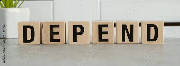 Fototapeta The word depend is written in wooden blocks on a gray surface