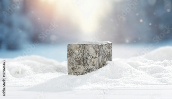 Fototapeta Winter landscape with fresh white snow and stone pedestal with copy space for product placement or text. Blurred background of snow-covered trees and blue winter sky and sunlight.