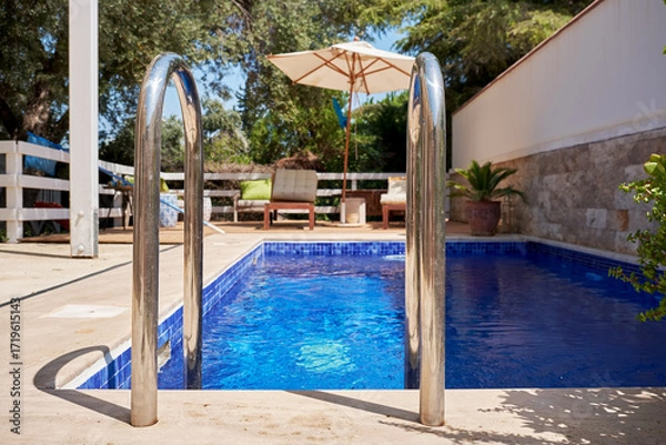 Fototapeta Chrome Ladder Entering a Refreshing Blue Swimming Pool