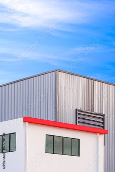 Fototapeta White industry office building in front of warehouse with gray corrugated steel wall against blue sky background in vertical frame, Modern geometric exterior industrial architecture design