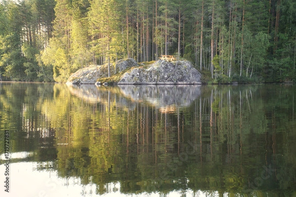 Fototapeta Lake landscape with a rocky island and a picnic table, surrounded by forest