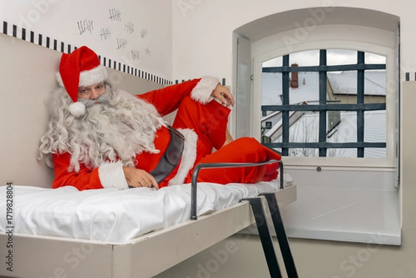 Fototapeta Santa Claus is resting on a bunk in a prison