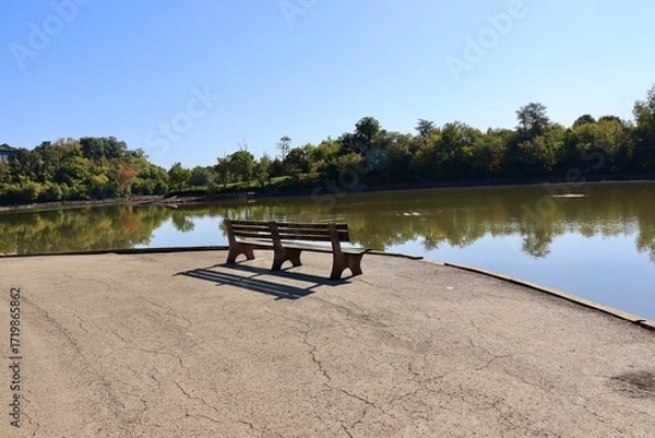 Fototapeta The empty wood bench at the lake in the park.