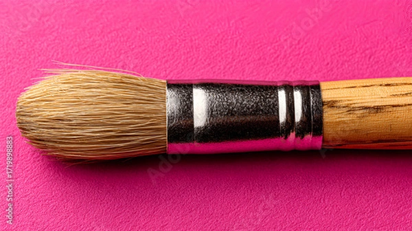 Fototapeta Close-up of a paintbrush with natural bristles resting on a vibrant pink surface, showcasing the texture and craftsmanship of artistic tools for creative expression