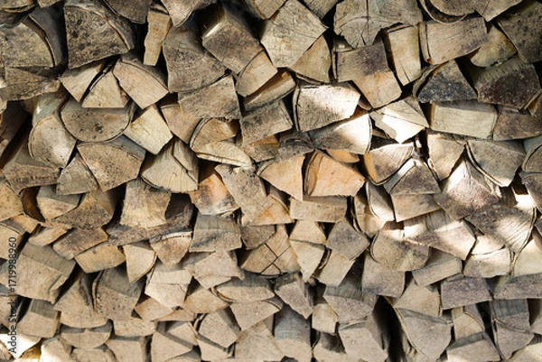 Fototapeta Stack of firewood logs neatly piled outdoors. Natural texture of chopped wood, rustic background, renewable energy source, eco-friendly fuel for fireplace, stove, or campfire. High quality photo