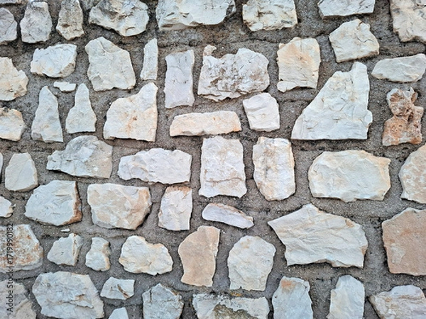 Fototapeta Natural stone wall texture before final plastering showcasing unique shapes and earthy tones
