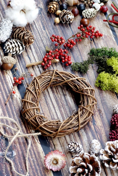 Fototapeta The materials for making Christmas wreaths on the table include cane rings, pine cones and ribbons. Christmas decoration.