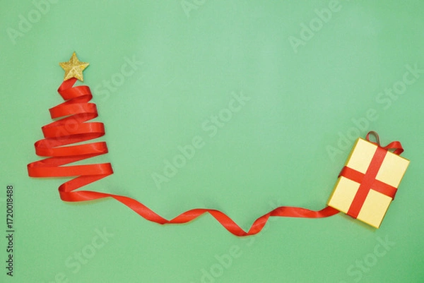 Fototapeta Red ribbon Christmas tree and gift box on green background. Christmas background.