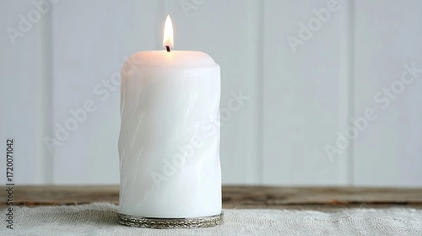 Fototapeta White Candle Flickering Softly on a Natural Fabric Surface With a Neutral Backdrop