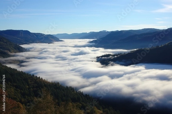 Fototapeta Serene valley shrouded in soft white clouds beneath blue sky mist mountains