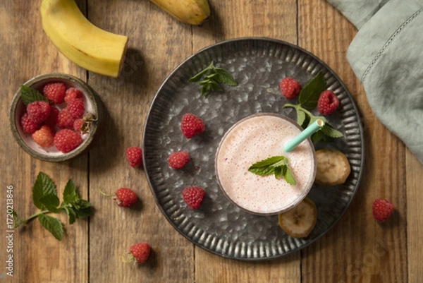 Fototapeta Refreshing banana raspberry smoothie with fresh mint for healthy living and summer enjoyment. Top view flat lay background.