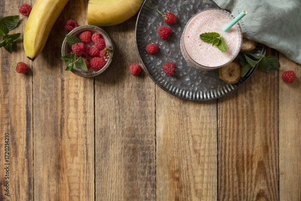 Fototapeta Refreshing banana raspberry smoothie with fresh mint for healthy living and summer enjoyment. Top view flat lay background.
