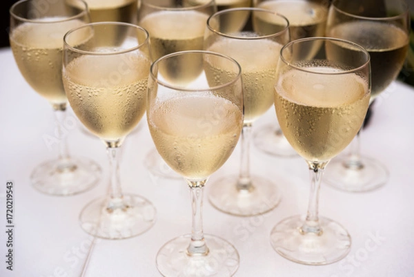 Fototapeta Elegant champagne glasses filled with sparkling wine on a festive celebration table, close up view of luxury drink serving for wedding banquet, party toast, event catering and reception ceremony