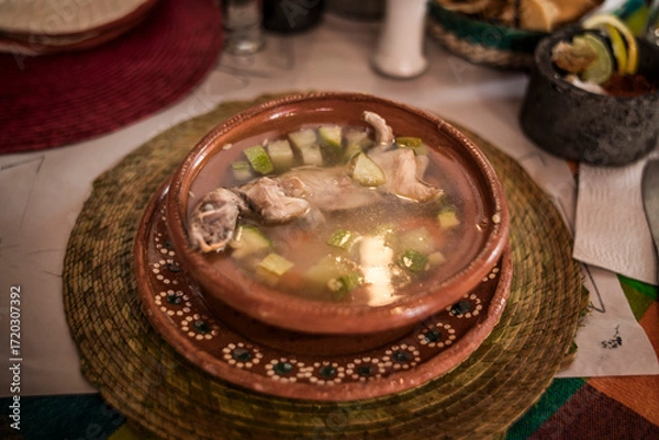 Fototapeta Rat broth, a typical dish from the state of Zacatecas, Mexico, accompanied by chopped vegetables and a whole field rat, served in a clay dish.
