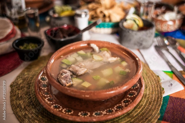 Fototapeta Rat broth, a typical dish from the state of Zacatecas, Mexico, accompanied by chopped vegetables and a whole field rat, served in a clay dish.
