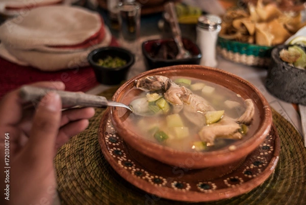 Fototapeta POV photo of Rat broth, a typical dish from the state of Zacatecas, Mexico, accompanied by chopped vegetables and a whole field rat, served in a clay dish.
