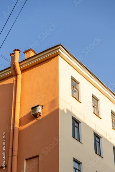Fototapeta Air conditioners on the facade of a yellow house against a blue sky. An air ventilation and cooling system and air purification technologies are installed. split system.