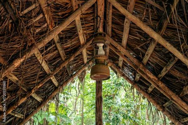 Fototapeta Thatched roof of cabin with a vintage lamp suspended under the wooden beams.