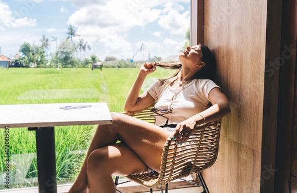 Fototapeta Young woman rests with eyes closed near table, moment of tech detox after digital overload, reflecting on mindful balance between online productivity and mental recharge.
