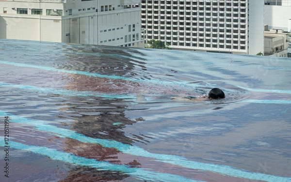 Fototapeta Unrecognizable person Swimming in Rooftop Pool with City View
