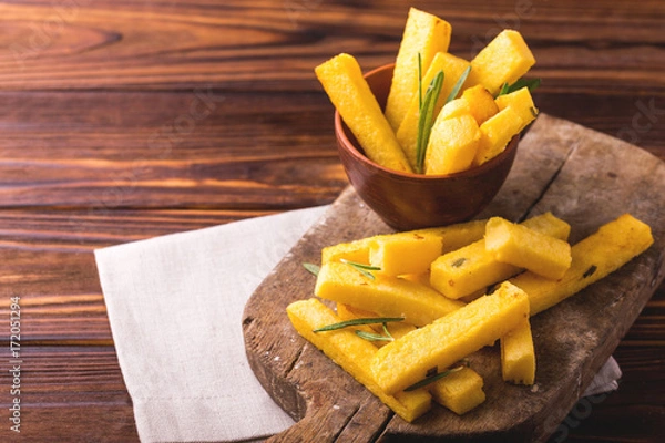 Fototapeta Polenta fries with rosemary. Italian appetizers. Horizontal view.