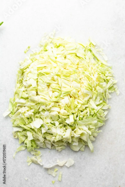 Fototapeta Overhead view of sliced cabbage on a marble countertop, top view of cabbage leaves being shredded, green cabbage being sliced