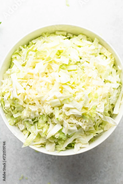 Fototapeta Overhead view of sliced cabbage on a marble countertop, top view of cabbage leaves being shredded, green cabbage being sliced