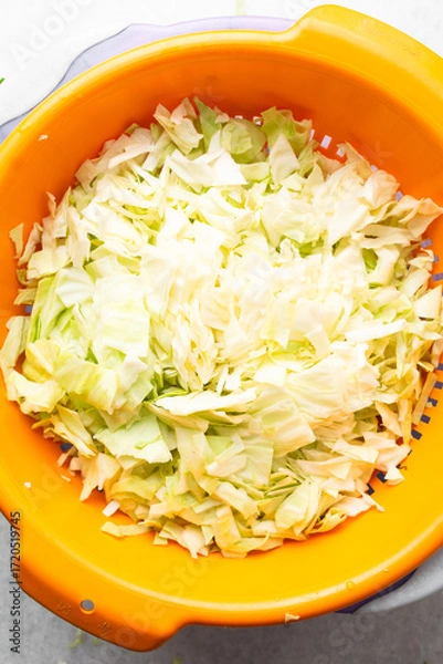 Fototapeta Overhead view of sliced cabbage on a marble countertop, top view of cabbage leaves being shredded, green cabbage being sliced