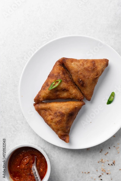 Fototapeta Overhead view of samosa on a white plate, top view of beef samosa on a white background