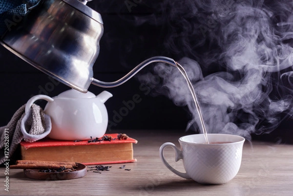 Fototapeta Hot tea is poured into glasses with steam. Teacups are placed on the table in the warm atmosphere of morning sunlight.
