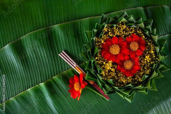 Fototapeta Krathong decorates with flowers that have blurred focus of 3 incense sticks and candle put on banana leaf for Loy Krathong festival.